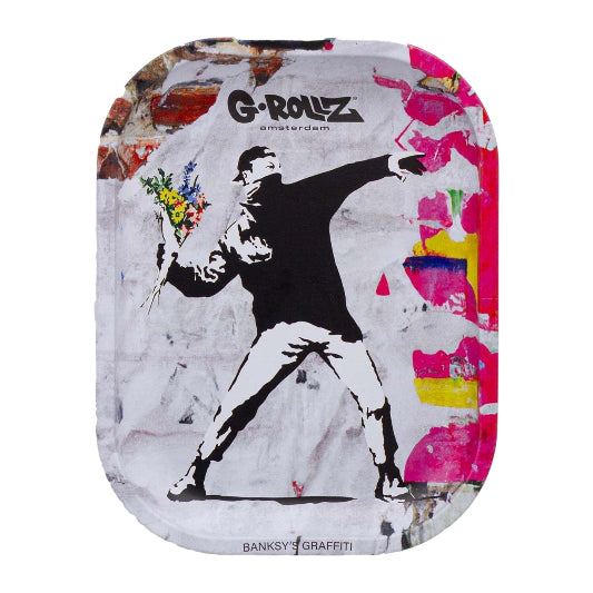 A rectangular rolling tray with rounded corners featuring a Banksy-style graffiti print. The design shows a black-and-white figure throwing flowers, with the text 'G-ROLLZ amsterdam' and 'BANKSY GRAFFITI' on a distressed multicolor background.