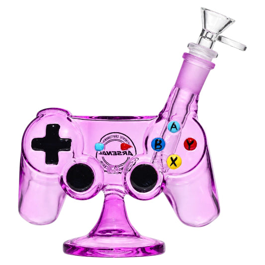 Purple Arsenal 7-inch glass bong shaped like a gaming controller, featuring a black directional pad, two black joysticks, colourful A, B, X, and Y buttons, angled clear glass bowl, and matching purple pedestal base.
