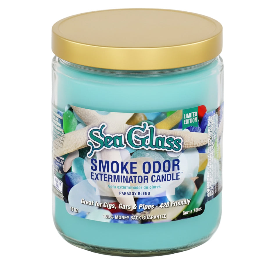 A Sea Glass Exterminator Candle in a clear glass jar with a gold lid and turquoise wax, featuring a colorful beach-themed label.