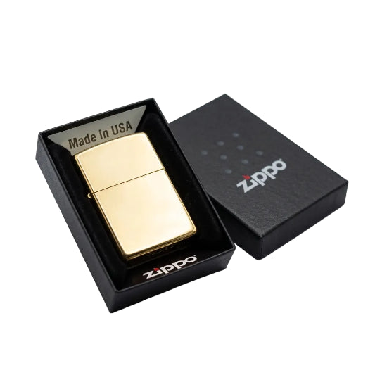 A gold Zippo lighter displayed next to its black presentation box, with the lighter inside an open black box labeled 'Made in USA' and the closed lid showing the Zippo logo.