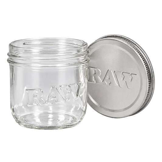 Clear RAW glass mason jar with raised RAW lettering on the front and a silver RAW-branded lid standing behind it.