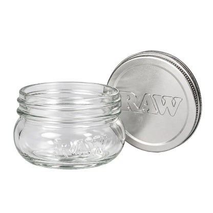 Small RAW glass mason jar with raised RAW lettering on the front and a silver RAW-branded lid placed behind it.