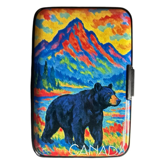 Slim hard shell Canada card wallet with a colourful textured oil painting style print of a black bear standing near a bright mountain lake, with red and blue mountains, yellow sky, and the word “CANADA” printed in white at the bottom. - The Wee Smoke Shop