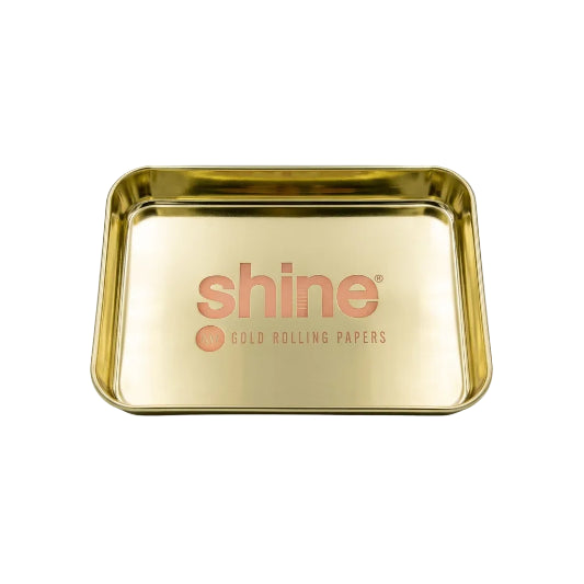 A shiny gold metal rolling tray with the brand name 'shine' and 'GOLD ROLLING PAPER' printed in orange on the bottom, shown on a plain white background.