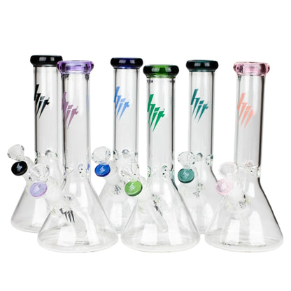 Group of HIT 10 inch clear glass beaker water pipes displayed together with black, purple, blue, green, teal, and pink accent colours on the mouthpieces, bowls, and logos. The Wee Smoke Shop