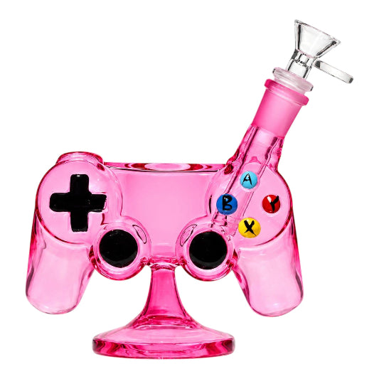Pink Arsenal 7-inch glass bong shaped like a video game controller, featuring a black directional pad, two black joysticks, colourful A, B, X, and Y buttons, angled clear glass bowl, and matching pink pedestal base.