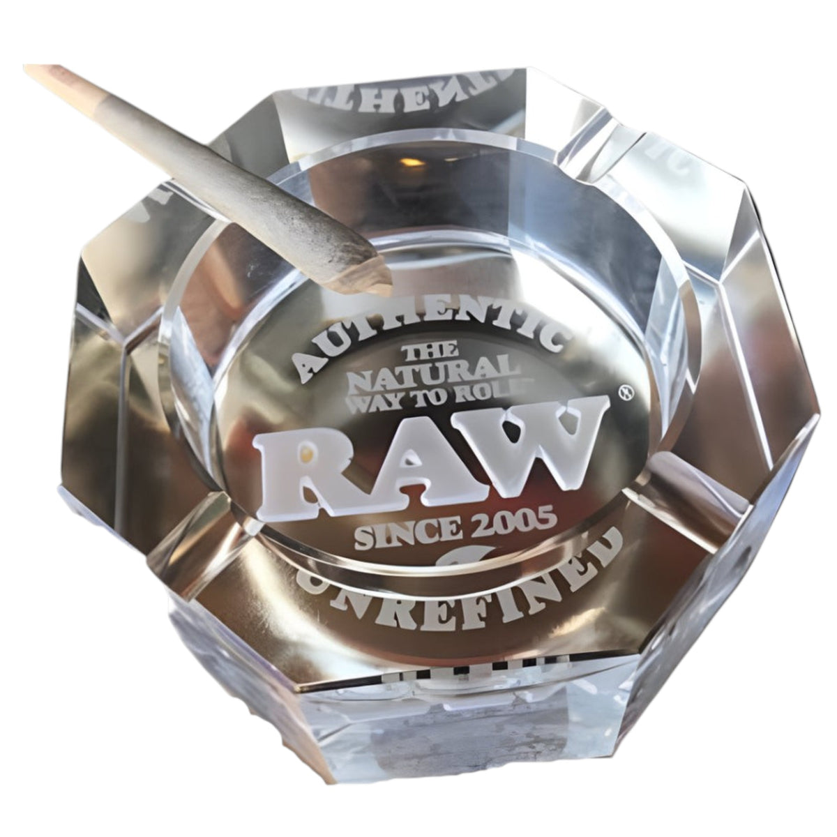 Clear faceted glass ashtray with white RAW branding and “Authentic, The Natural Way to Roll, Since 2005” text printed inside, shown with a rolled cone resting on the edge. The Wee Smoke Shop