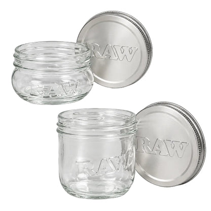 Two clear RAW glass mason jars shown with silver RAW-branded lids, featuring raised RAW lettering on the glass and embossed RAW text on the lids.
