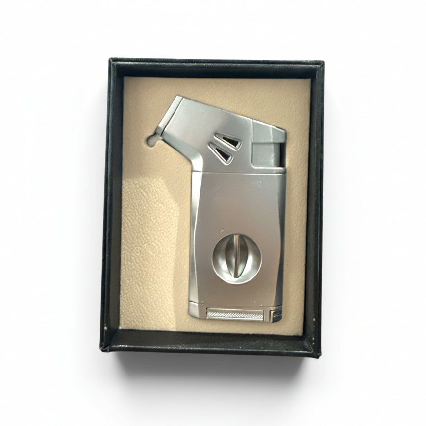 A silver metallic cigar cutter and lighter set presented inside a black gift box with a beige insert, photographed from above on a white background.