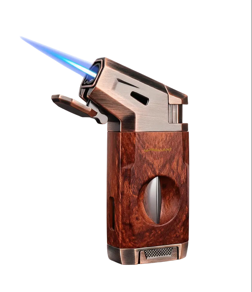 A premium cigar torch lighter with a rich wood grain finish and bronze-toned metal accents, shown with its blue jet flame ignited, alongside an open presentation box and a smaller inset showing the lighter closed.
