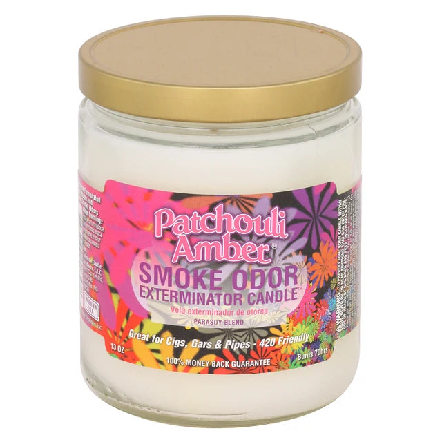 Patchouli Amber Smoke Odor Exterminator Candle in a clear glass jar with a gold metal lid and a colorful floral label, shown on a white background.