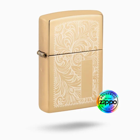 A gold-finished Zippo-style lighter with an engraved floral pattern on the front, shown on a light gray background with a circular 'Authentic Zippo Made in USA' badge near the lower right.
